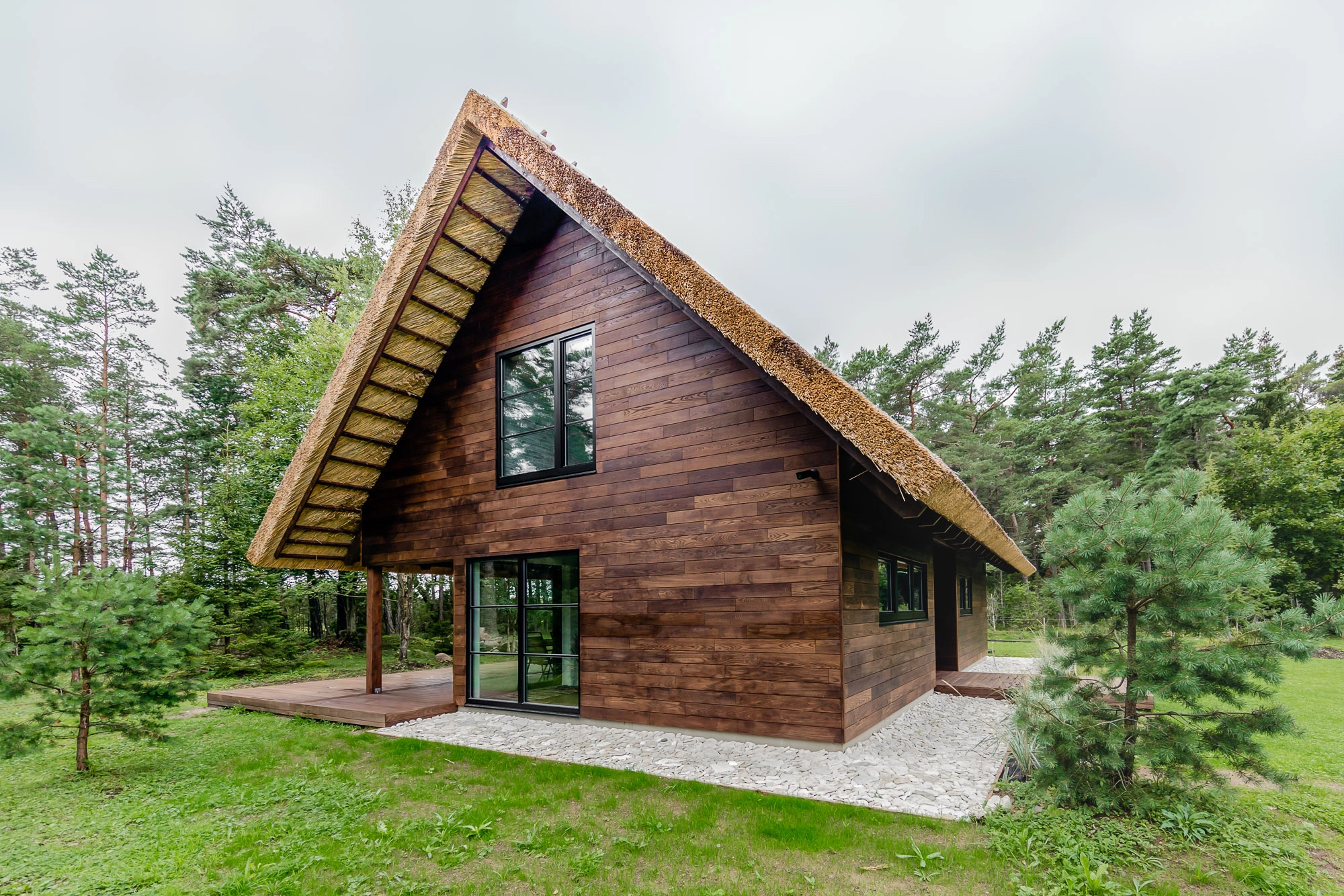 Zrównoważony dom w elewacji drewnianej i dachem pokrytym strzechą